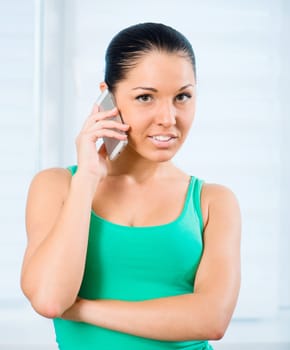 young smiling brunette woman talking by the phone at home