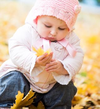 little baby in the park with autumn leaves
