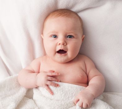 beautiful baby is hiding under the white blanket