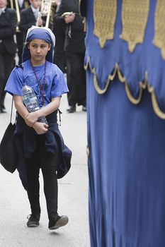 Girl dressed as a costalero behind a throne during a procession during Holy Week, Spain