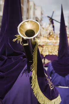 penitent purple tunic holds a trumpet during Holy week procession, Spain