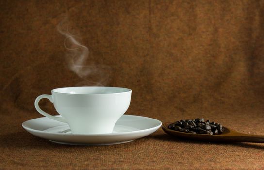 coffee cup and a spoon of baens still life on brown background.