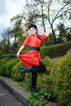 Attractive young girl in a red shirt walks in the city park