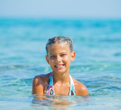 Portrait of cute girl swimming in the transparent sea