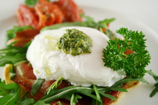 Poached egg with pesto, bacon, greens and sun dried tomatoes.