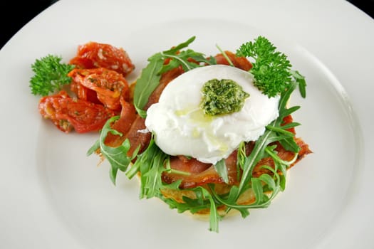Poached egg with pesto, bacon, greens and sun dried tomatoes.