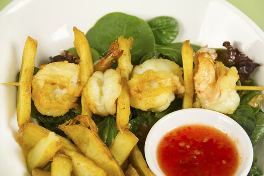Yummy fried shrimp and chip skewers with sweet chilli sauce ready to serve.