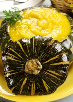 Pumpkin soup prepared in a pumpkin with the top sliced off.