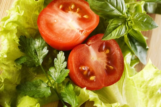 Sliced ??tomato, lettuce, basil and parsley. Preparation of salad.