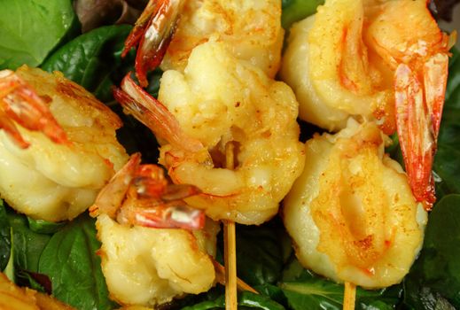 Yummy fried shrimp skewers on a bed of lettuce ready to serve.