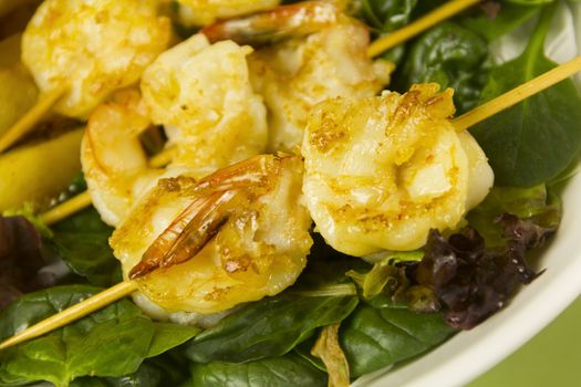 Yummy fried shrimp skewers on a bed of lettuce ready to serve.