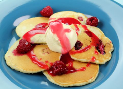 Delicious raspberry pancakes with raspberry sauce and a dollop of cream.