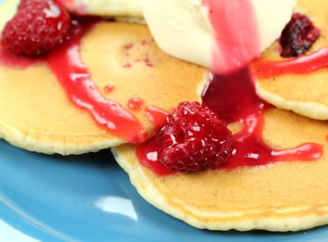 Delicious raspberries on pancakes with raspberry sauce and a dollop of cream.