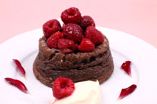 Delicious chocolate dessert topped with fresh raspberries and a dollop of cream.