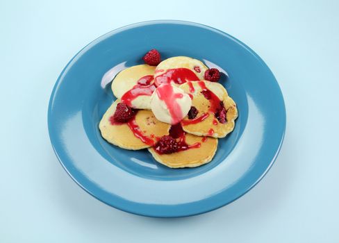 Delicious raspberry pancakes with raspberry sauce and a dollop of cream.