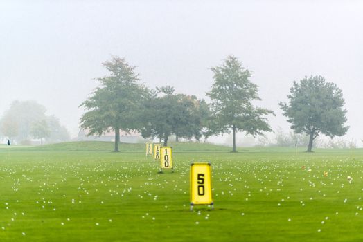 Yard signs in driving range and golf balls