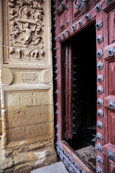 Entrance wooden door to the chapel of El Salvador, lintel carved stone, renaissance style, Ubeda, Jaen province, Spain