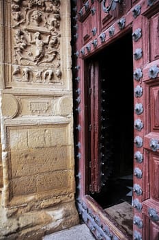 Entrance wooden door to the chapel of El Salvador, lintel carved stone, renaissance style, Ubeda, Jaen province, Spain