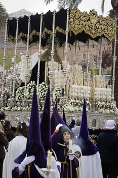 Detail penitent white holding a candle during Holy Week, Spain