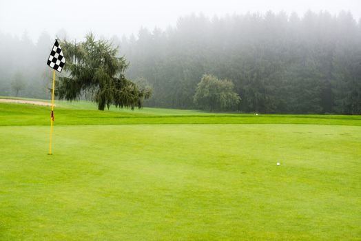 golf ball on green with target flag on beautiful golf course