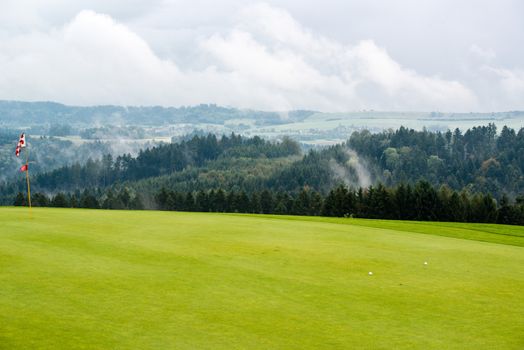 golf ball on green with target flag on beautiful golf course