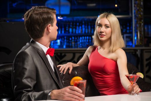 portrait of a woman in a nightclub, sitting on the couch and talking with man