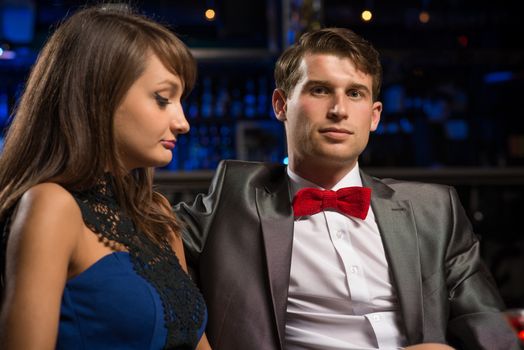 portrait of a man in a nightclub, sitting on the couch and talking with woman