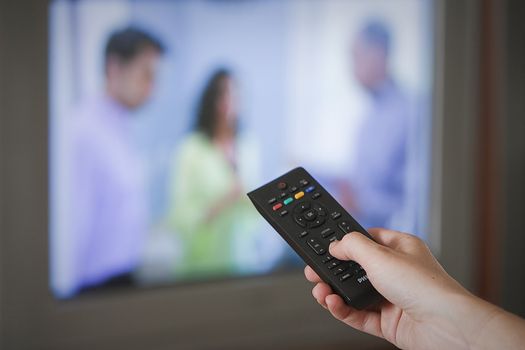 Hand holding remote control of a television