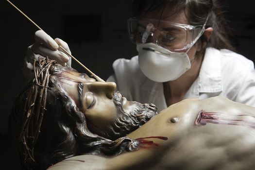 Cleaning of the face of a wooden sculpture of Christ crucified with an isopo impregnated with dimethylformamide, Andalusia, Spain