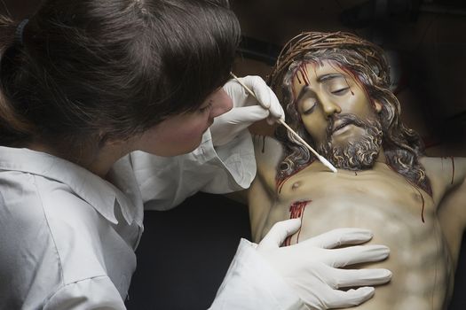 Cleaning of the face of a wooden sculpture of Christ crucified with an isopo impregnated with dimethylformamide, Andalusia, Spain