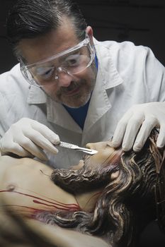 Professional Restorer with a scalpel repairing a sculpture of the crucified Christ, Andalusia, Spain