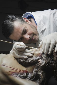 conservative restoring an image of Christ crucified on Carving wood, Andalusia, Spain