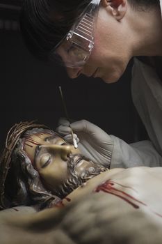 Cleaning of the face of a wooden sculpture of Christ crucified with an isopo impregnated with dimethylformamide, Andalusia, Spain