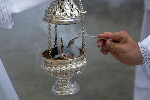 Altar boy looking with a silver spoon incense in a censer during a procession of holy week, Andalucia, Spain