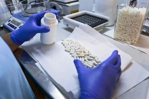 Packing white capsules in a boat in a pharmaceutical laboratory, Spain