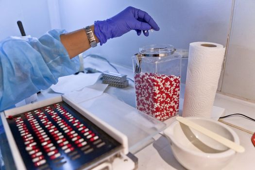 Packing white and red capsules in a sorting machine in a pharmaceutical laboratory, Spain