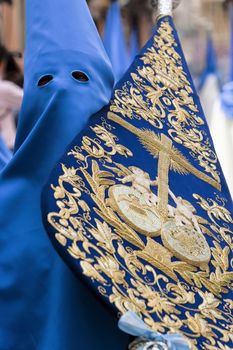  penitent wearing flag with coat of arms of brotherhood during holy week procession, palm Sunday, Linares, Jaen province, Andalucia, Spain