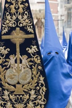 penitent wearing flag with coat of arms of brotherhood during holy week procession, palm Sunday, Linares, Jaen province, Andalucia, Spain