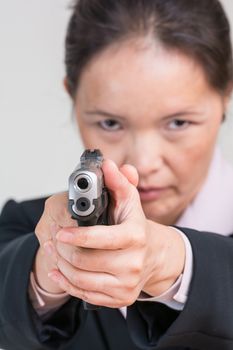 Close up portrait of woman in business suit aiming a hand gun at you