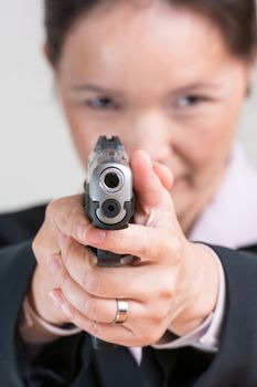 Close up portrait of woman in business suit aiming a hand gun