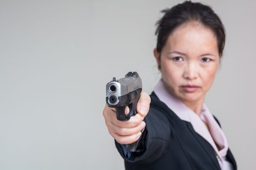 Close up portrait of woman in business suit aiming a hand gun