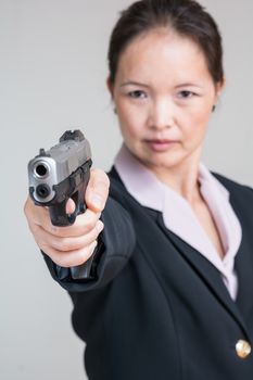 Close up portrait of woman in business suit aiming a hand gun