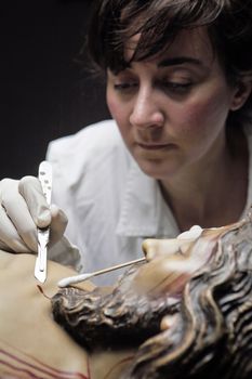 conservative restoring an image of Christ crucified on wood, Andalusia, Spain