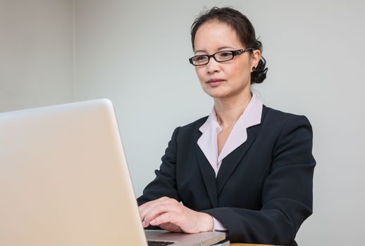 Professional woman in business suit working and typing on laptop