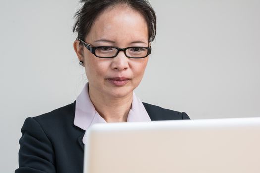 Professional woman in business suit working and typing on laptop