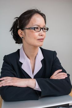 Professional woman in business suit with a closed laptop on desk