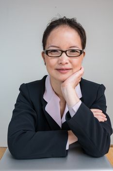 Professional woman in business suit with a closed laptop on desk