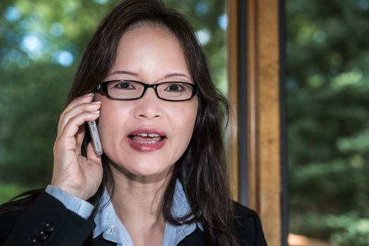 Woman in business suit speaking on a cellphone in front of a window