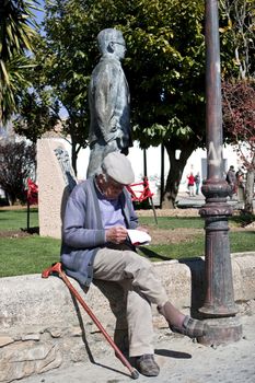 Old man reading relaxing in the Park next to the statue of Blas Infante in Ronda, Malaga Province, Andalucia, Spain