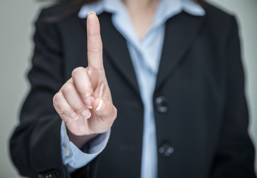 Professional woman in business suit shaking one finger and denying on grey background 